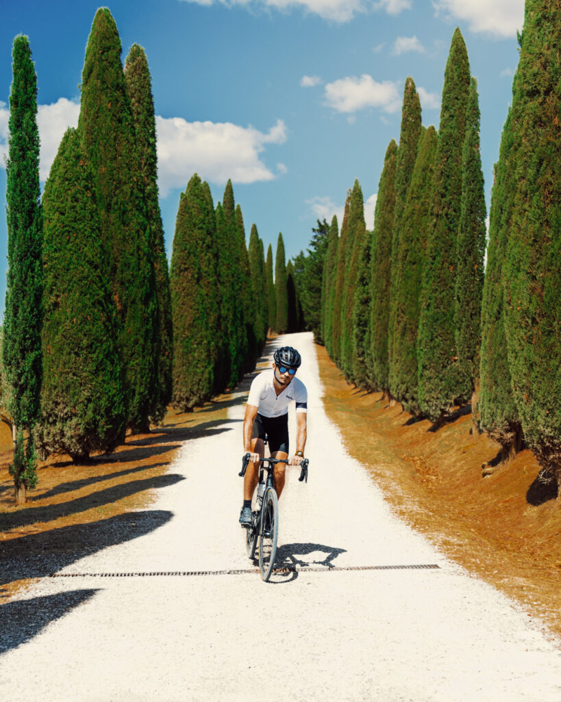 Cyclist on an e-bike exploring a white country road, framed by the classic cypress-lined landscape of Tuscany.