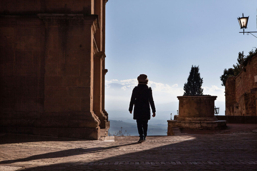 Woman walking by Pienza Cathedral with Val d’Orcia view, Tuscany near Villa Montelandi