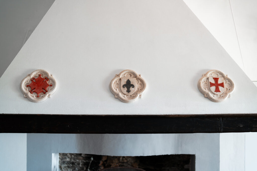 Close-up of hand-carved stone emblems above the fireplace at Villa Montelandi, showcasing traditional Tuscan craftsmanship and historic design details.