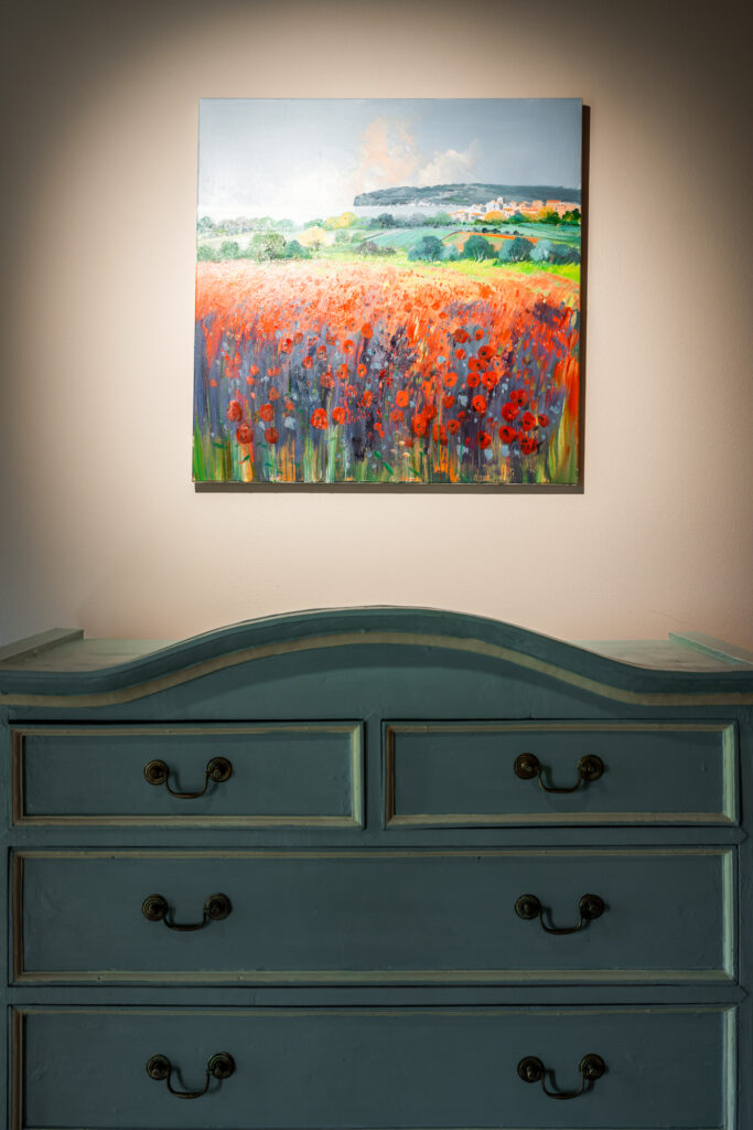 Detail of a turquoise dresser and colorful poppy painting in a Tuscan bedroom at Villa MonteLandi, combining art, color, and timeless elegance.
