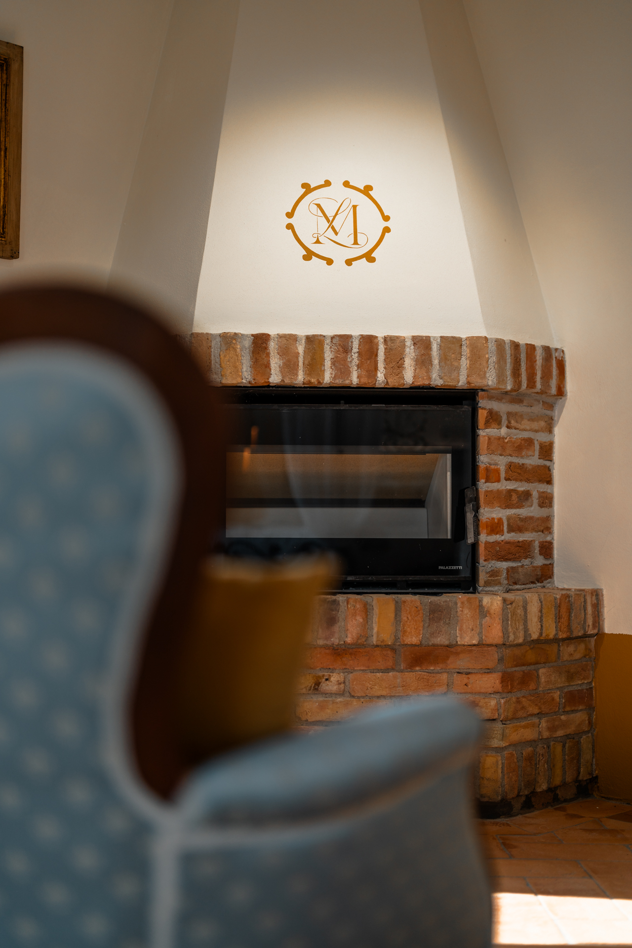Detail of a brick fireplace with the Villa MonteLandi emblem, symbol of refined Tuscan craftsmanship and cozy elegance in the heart of Val d’Orcia.